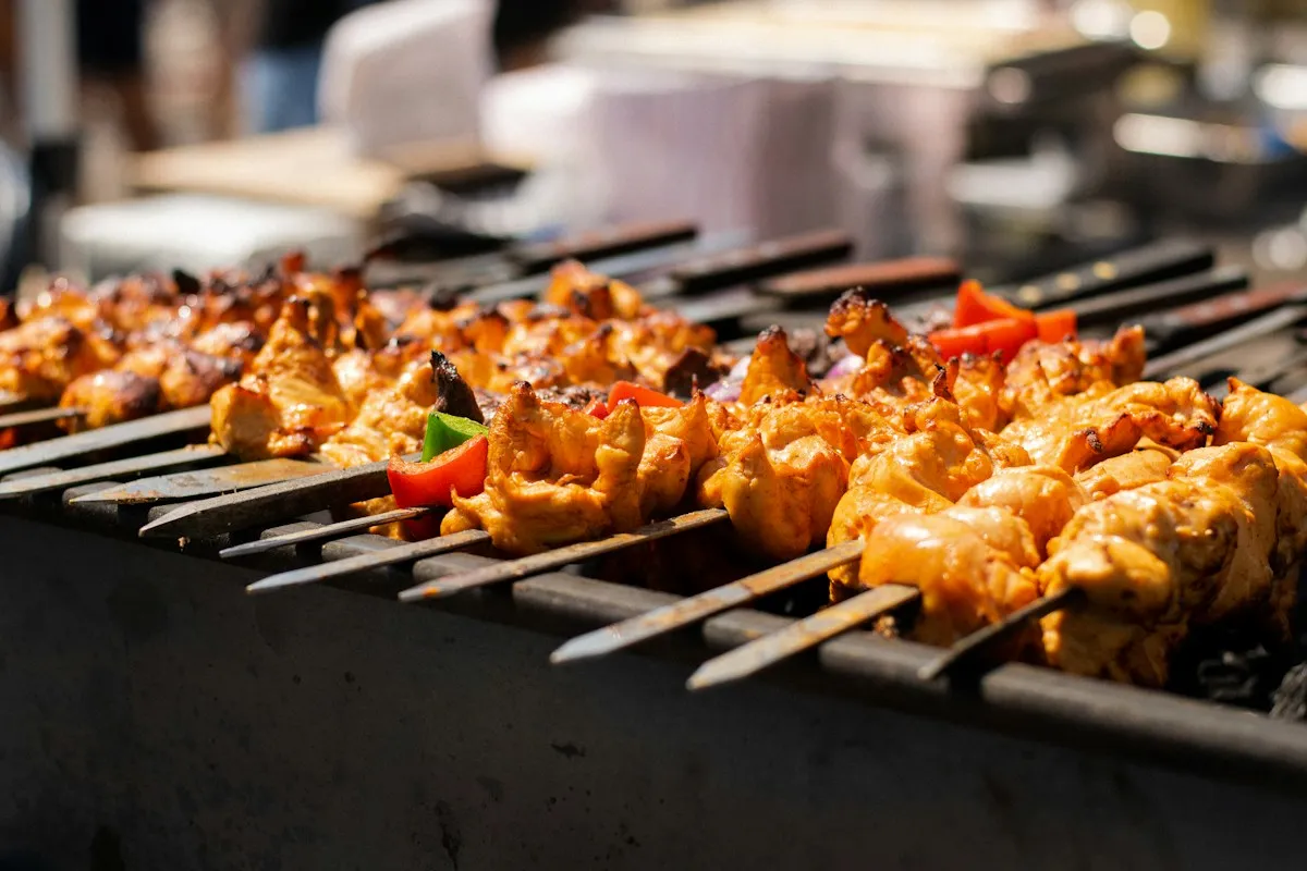 Rows of chicken and pepper skewers cooking on a grill