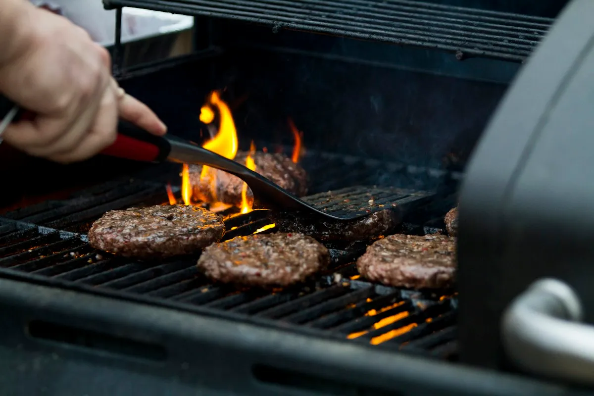 Burgers on a gas barbecue being turned with tongs