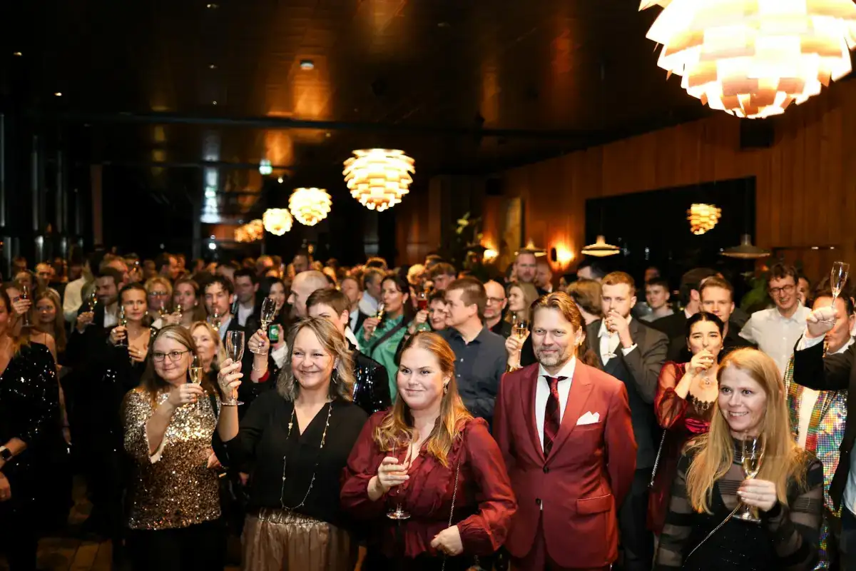 A crowd of guests with drinks at an indoor evening event