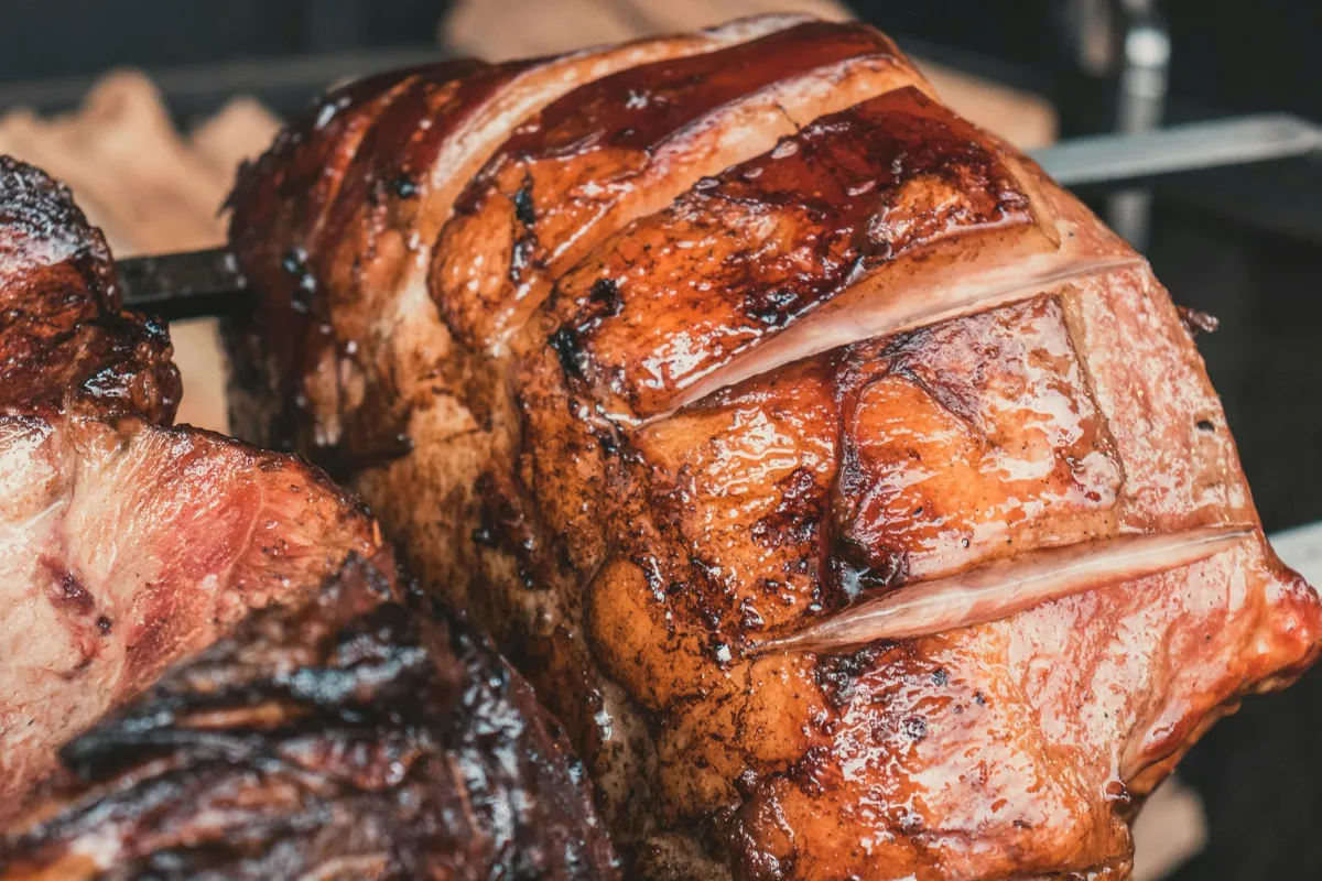 Scored pork with golden crackling roasting on a spit